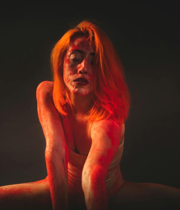 Woman performing a graceful yoga stretch in dark studio.